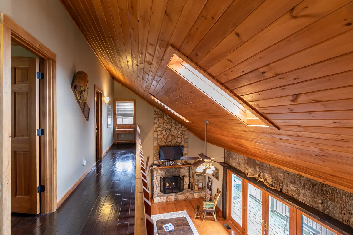 A rustic yet elegant living area with a striking stone fireplace, expansive windows letting in natural light, and wooden ceilings. The space exudes warmth, with comfortable seating and decor that invites relaxation and intimate conversations.