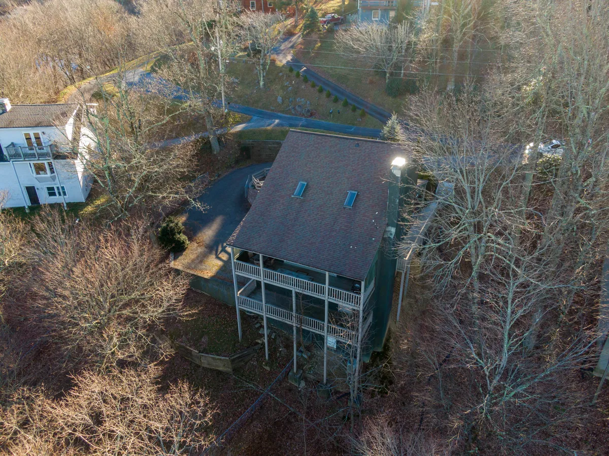 A peaceful exterior shot of the house surrounded by tall trees, with a visible driveway and a welcoming porch. The setting exudes tranquility and a sense of retreat, with ample space for outdoor activities and relaxation.
